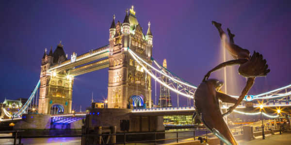 The lady and the dolphin fountain with Tower Bridge at night, London, UK