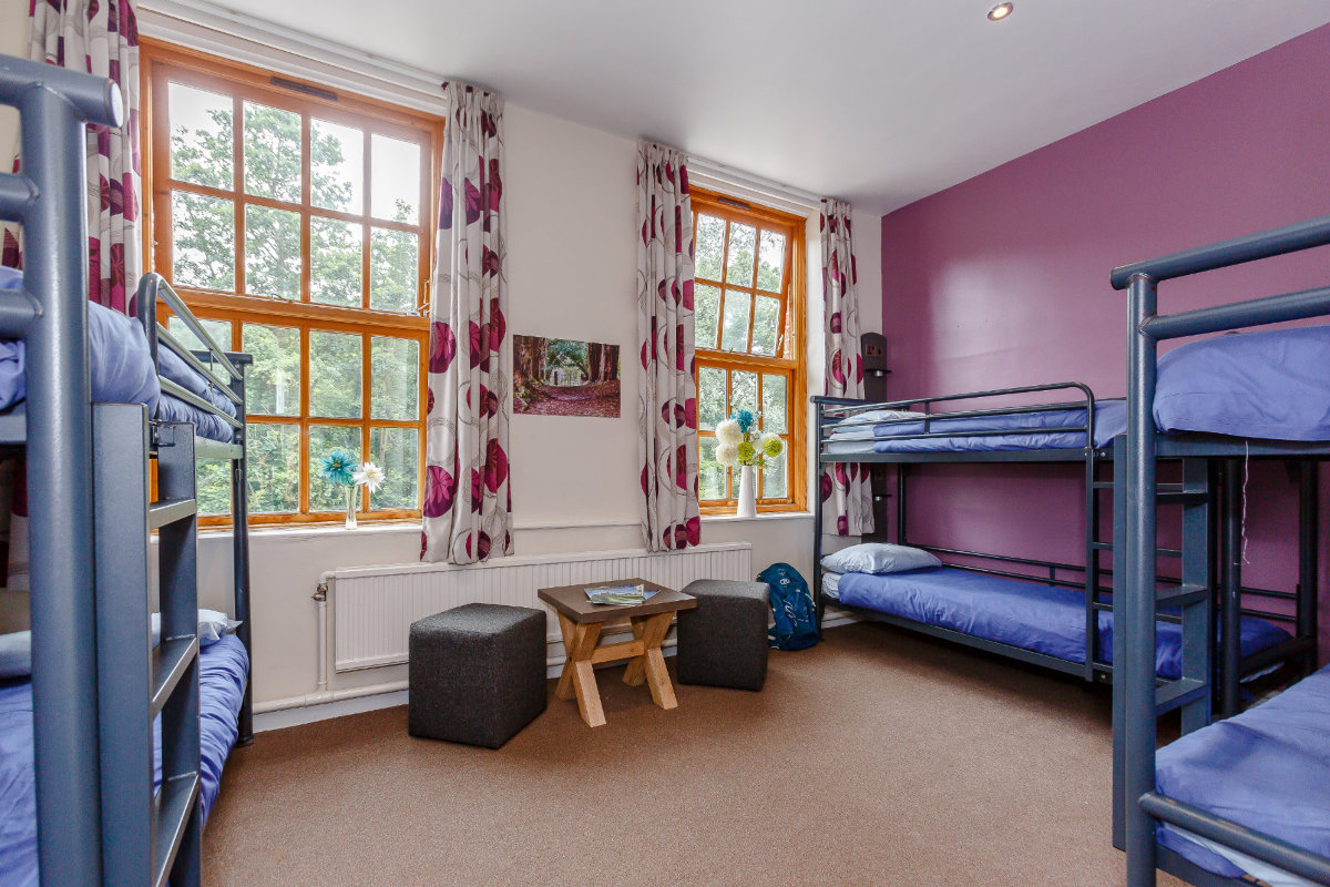 Bedroom with purple wall and seating area atYHA Osmotherley